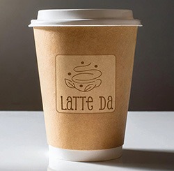To go coffee cup with a stylish decorative coffee cup underneath is written Latte Da in a fun handwritten script.